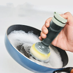 Hand holding soap dispensing dish brush with bristle head dripping water